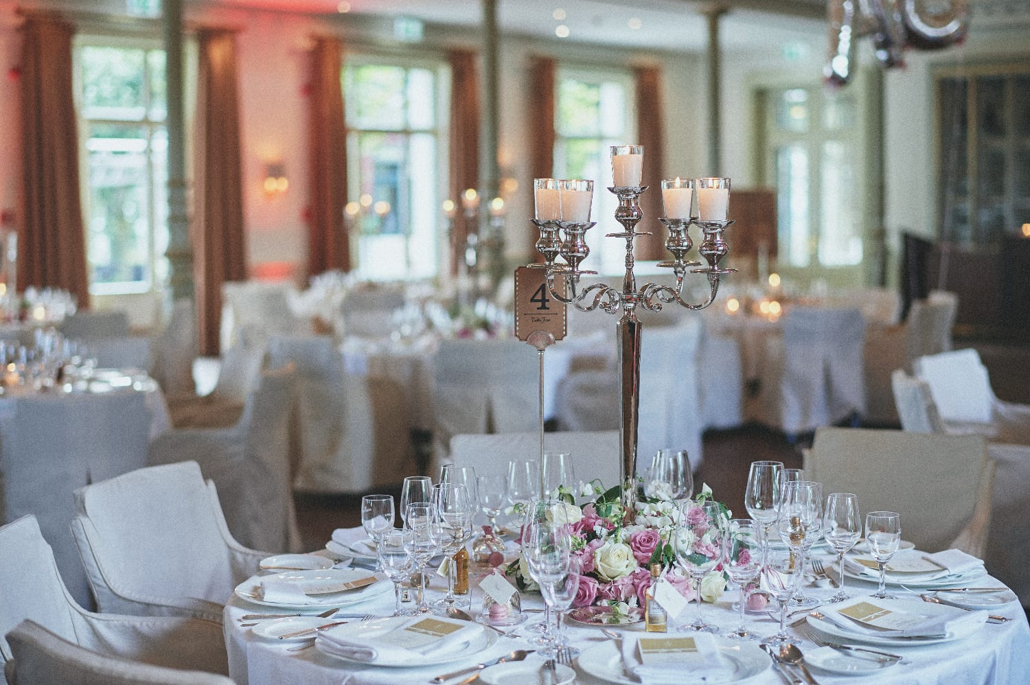Gedeckter Tisch mit Kerzenständer und rosa Blumen