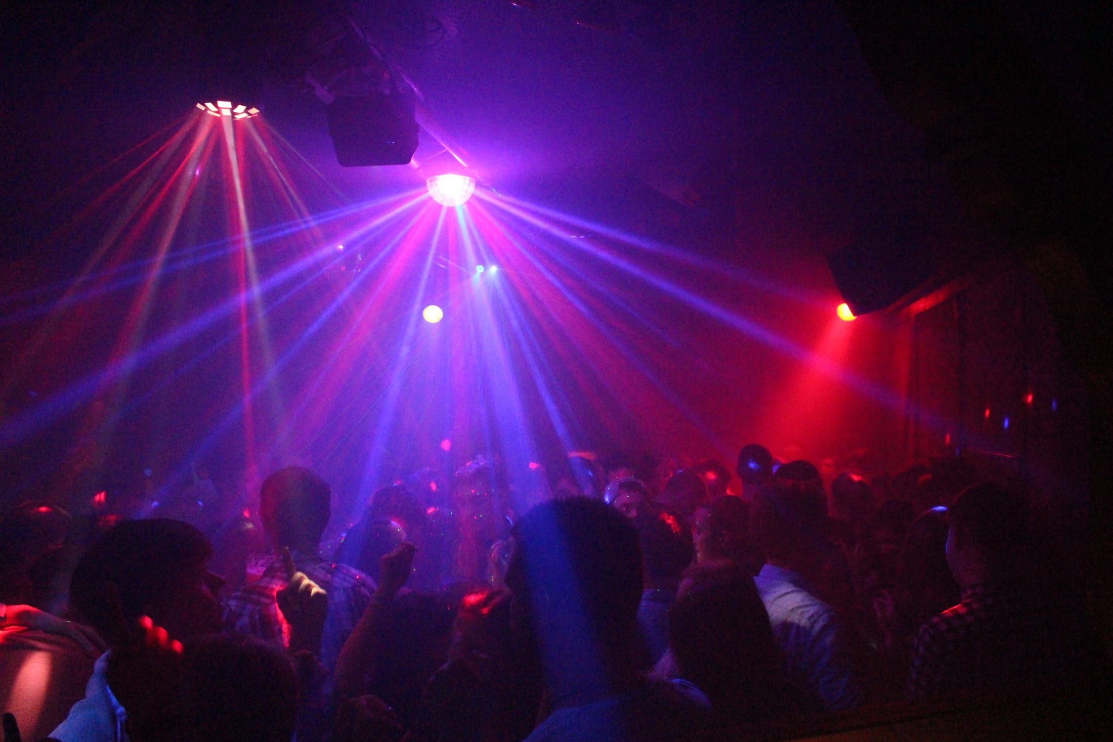 Partycrowd unter violetten Lichtstrahlen