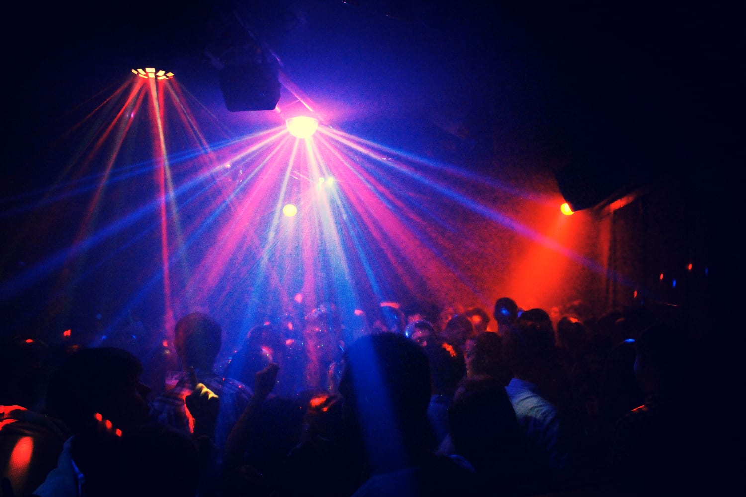 Partycrowd unter pinken und blauen Lichtstrahlen