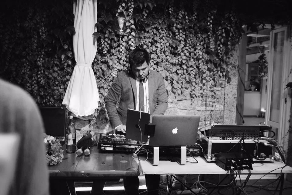DJ hinter dem MacBook bei einer Hochzeit im Freien, schwarz-weiß